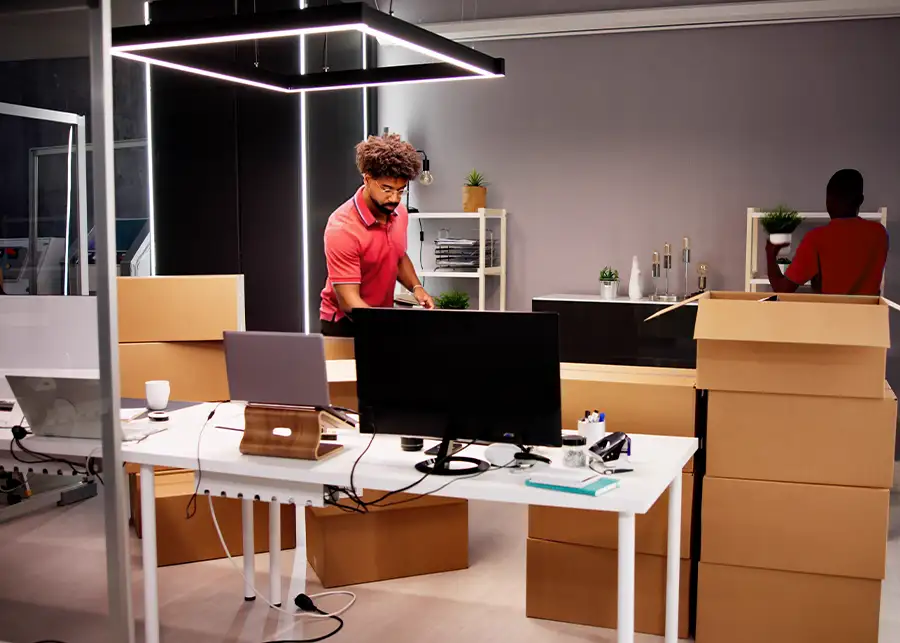 Two Moscardelli Moving & Storage crew members packing and organizing cardboard boxes throughout a commercial office space, after hours for office relocation in Springfield, IL