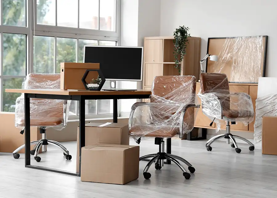 A fully wrapped and packed Springfield IL office with plastic-covered chairs, cardboard boxes, and furniture ready for moving