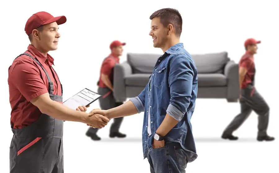 A Moscardelli Moving & Storage crew leader shaking hands with a satisfied Springfield, IL customer while movers carry a sofa in the background