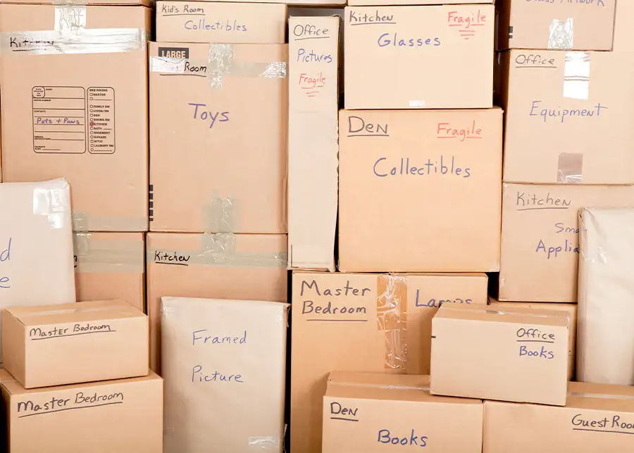 A wall of carefully labeled and organized moving boxes marked by room — Kitchen, Master Bedroom, Office, Den — packed by Moscardelli Moving & Storage in Springfield, IL