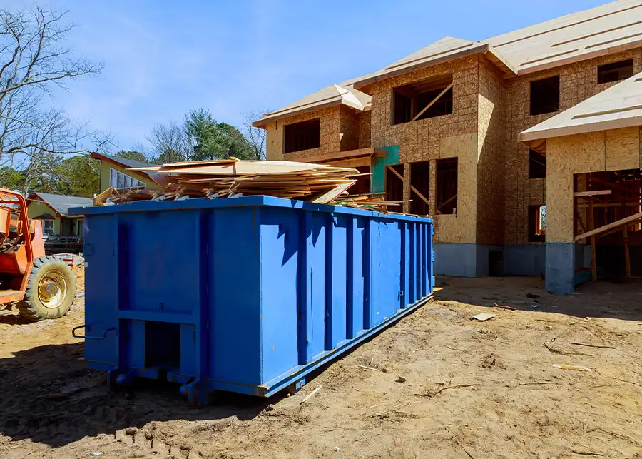 A blue roll-off dumpster filled with construction lumber debris parked at a new home build site in Springfield, IL served by Moscardelli Moving & Storage